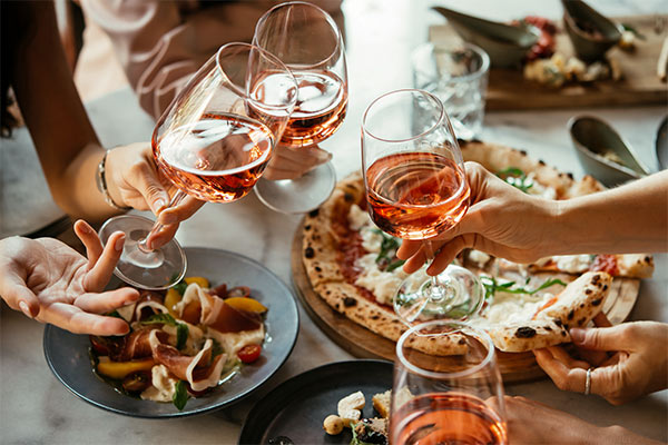 3 wines held above tasty pizzas and pastas