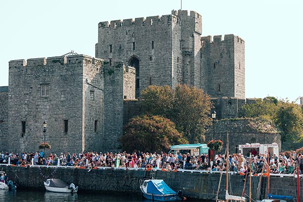 A crowd of people in front of Castle Rushen on a sunny day