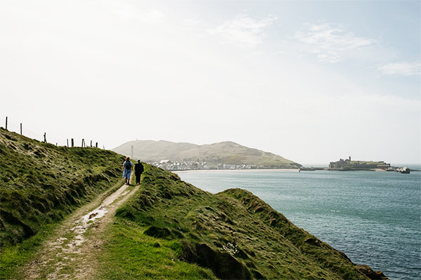 Two people walking along the coastal path towards Peel on the Isle of Man