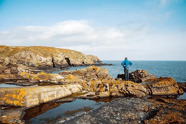 Someone stood on the rocks at Port Grenaugh on the Isle of Man