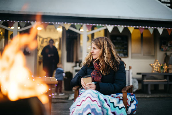 Someone sat by a fire with a blanket over their knees at The Shed café on the Isle of Man