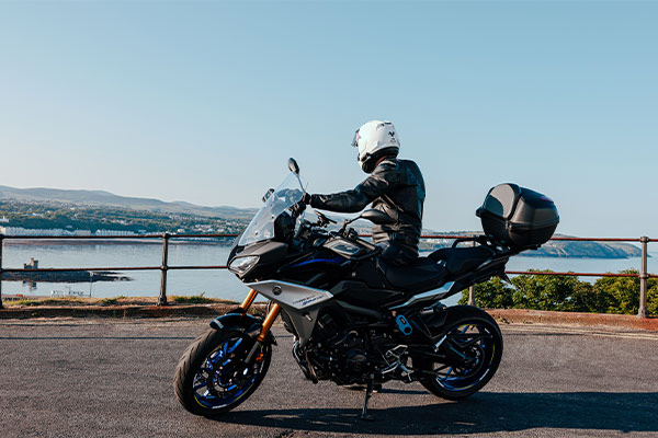 A person on a motorbike looking out to sea at Douglas Head on the Isle of Man during the TT