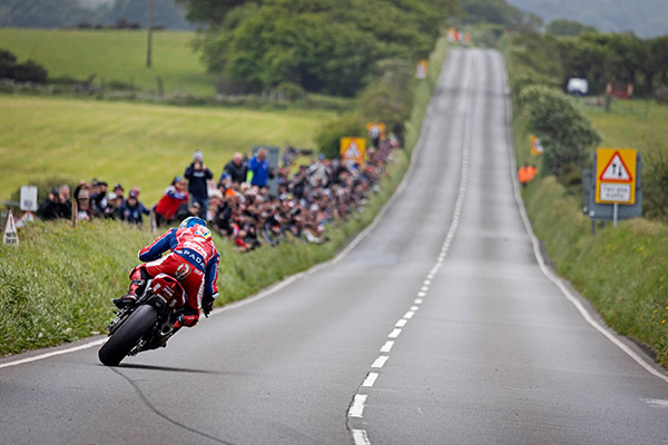 Dean Harrison racing in the Isle of Man TT at Creg-na-Baa as a crowd watches